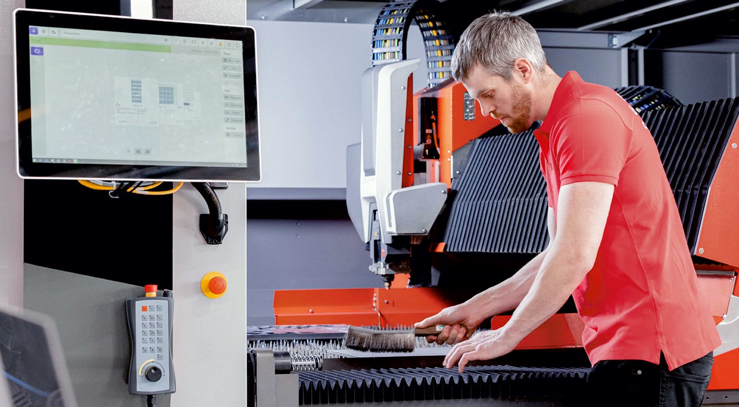 A man works diligently on a machine in a factory, highlighting Bystronic's role in supporting automotive and aerospace manufacturing.